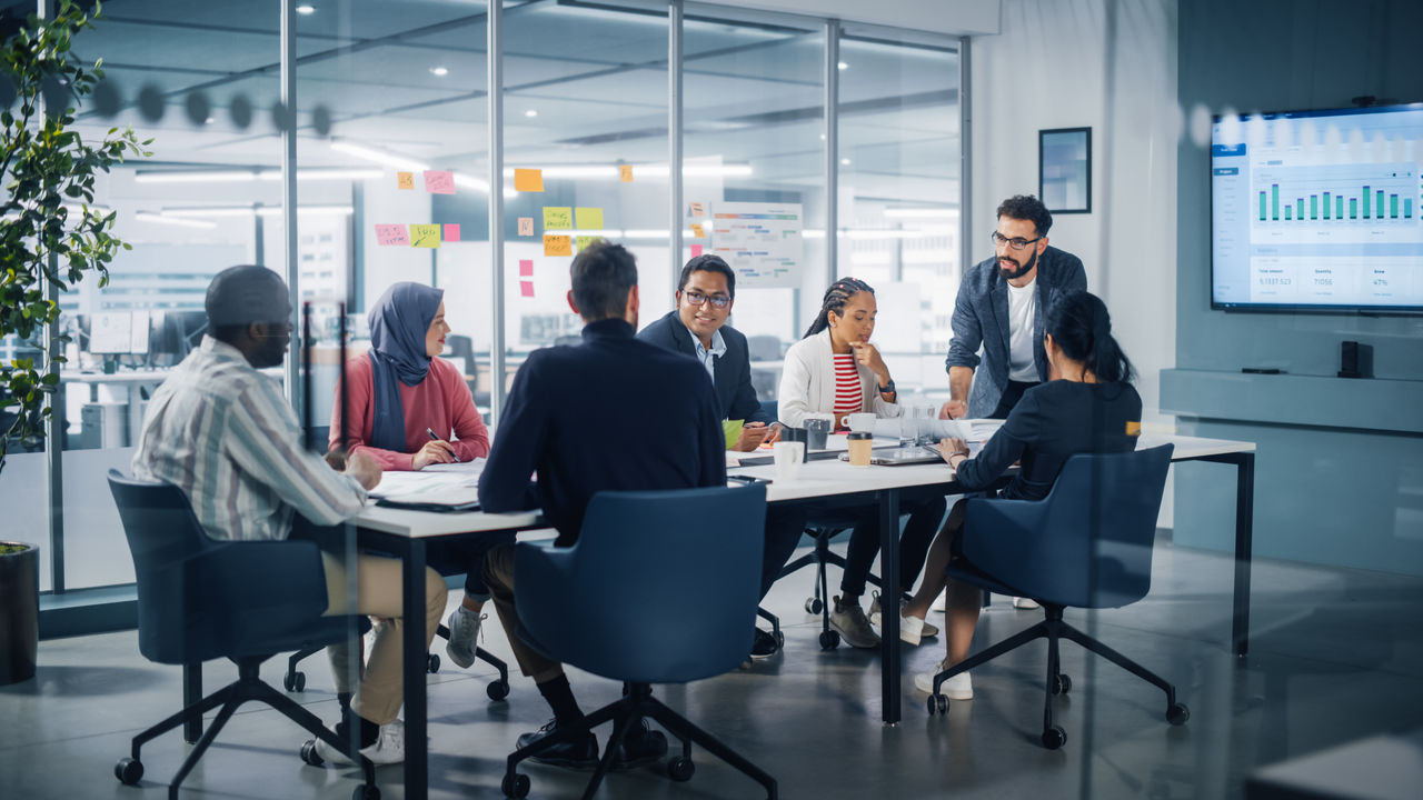 Multi-Ethnic Office Conference Room Meeting: Diverse Team of Young Entrepreneurs, Specialists Talk, Use TV for infographics. Smiling Businesspeople Discuss Investment Strategy in e-commerce Startup; Shutterstock ID 2101929376; purchase_order: -; job: -; client: -; other: -