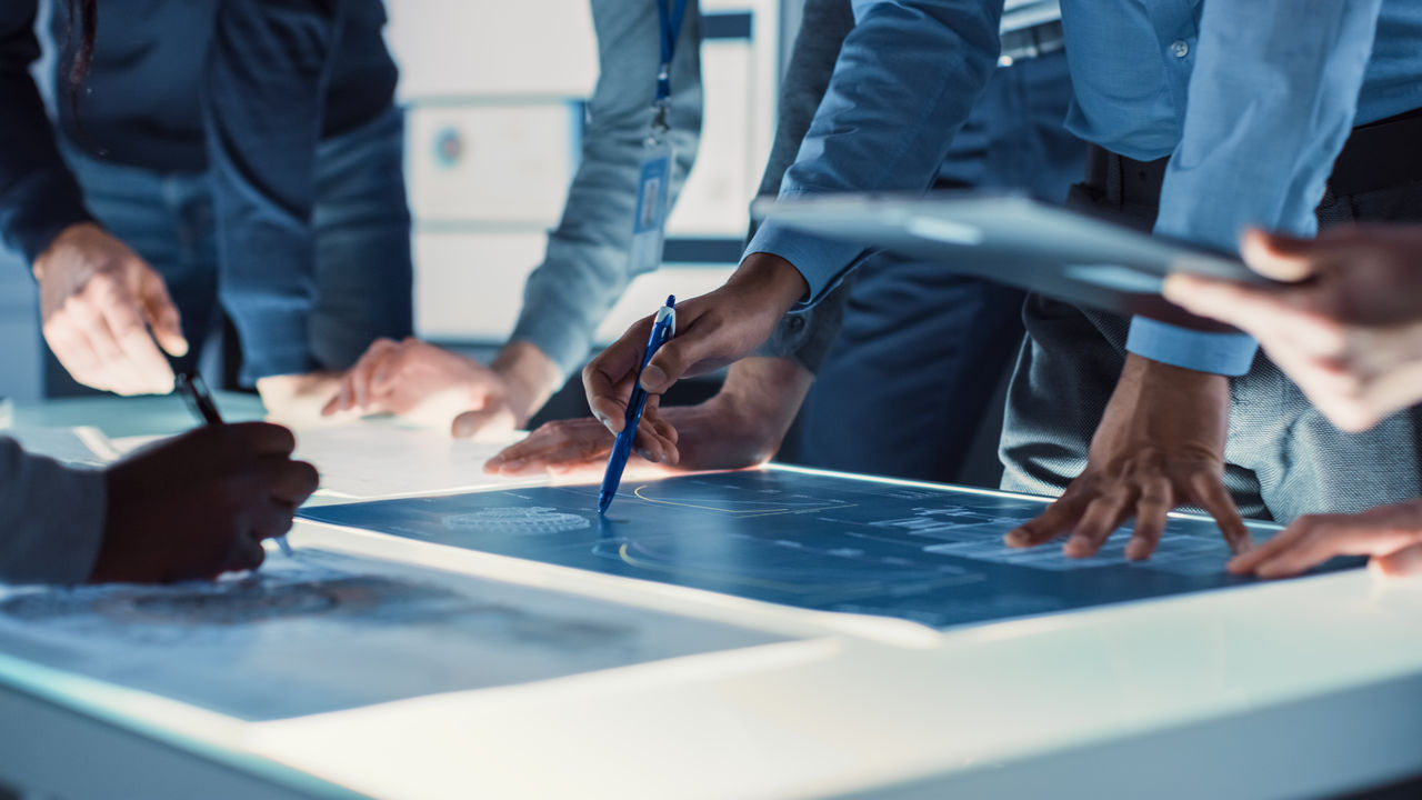 Engineer, Scientists and Developers Gathered Around Illuminated Conference Table in Technology Research Center, Talking, Finding Solution and Analysing Industrial Engine Design. Close-up Hands Shot; Shutterstock ID 1682713573; purchase_order: -; job: -; client: -; other: -