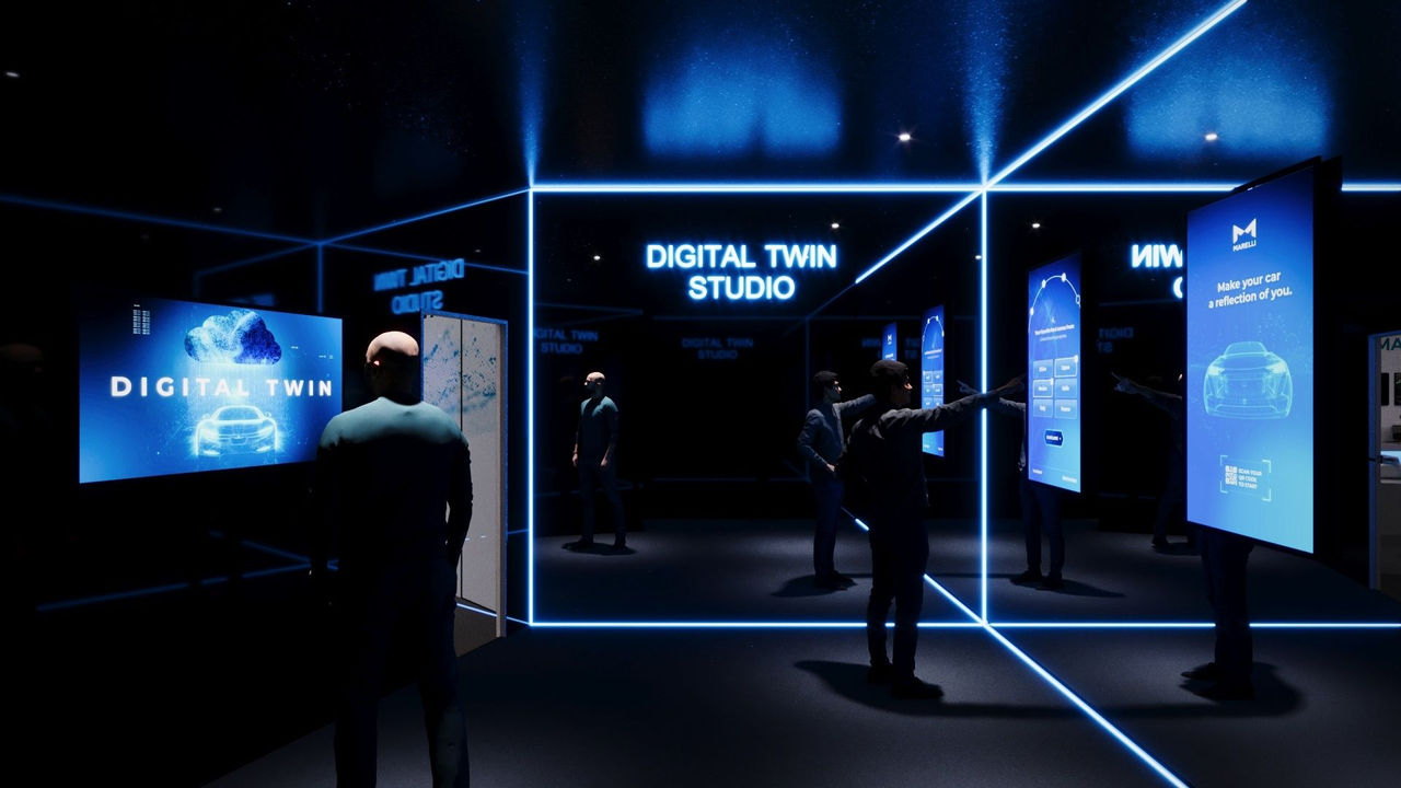Futuristic room with walls made of mirrors, illuminated with blue LEDs at the edges of the mirrors and with touch bluescreens on them. On the front mirror there is the writing in blue LED "Digital twin studio". A man from behind looks at one of the screens, another in profile is intent on touching a touch screen.